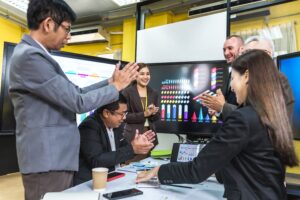 Men and women in an office celebrating the company's profit margin increase