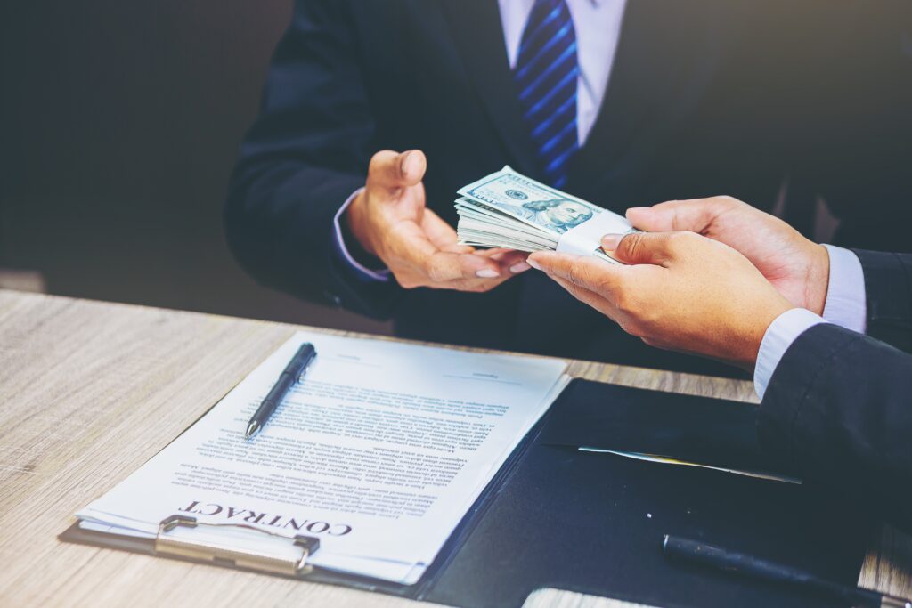 Businessman closing a deal and handing over a cash loan to business owner