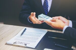 Businessman closing a deal and handing over a cash loan to business owner
